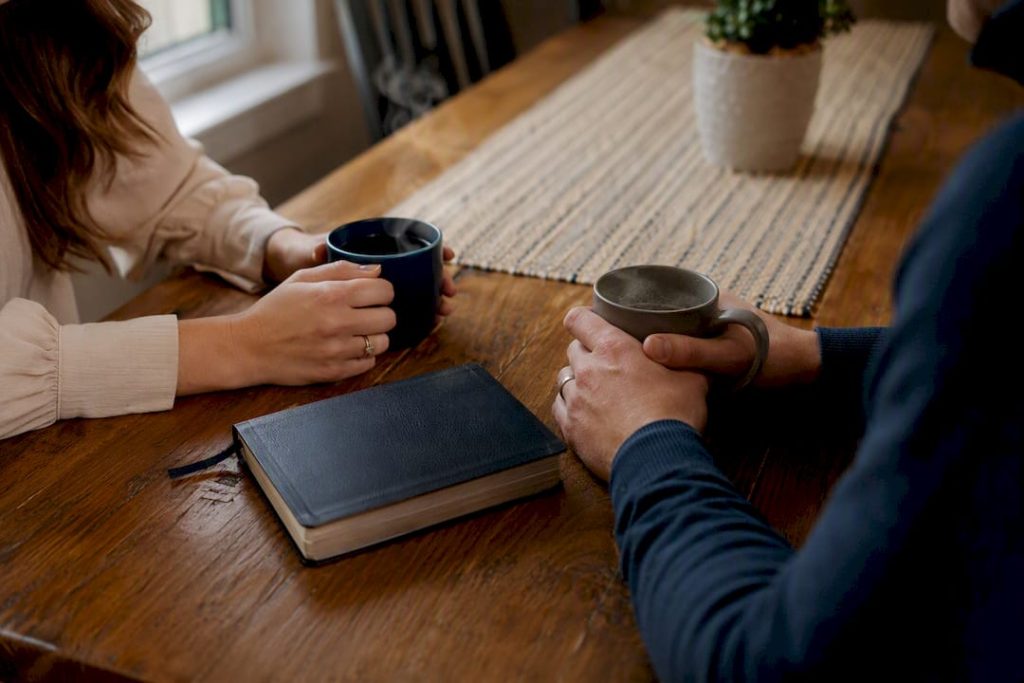 Engaged couple's hands with Bible and mugs